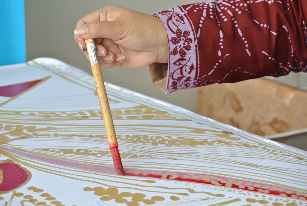 A hand of someone creating traditional Malaysian batik.